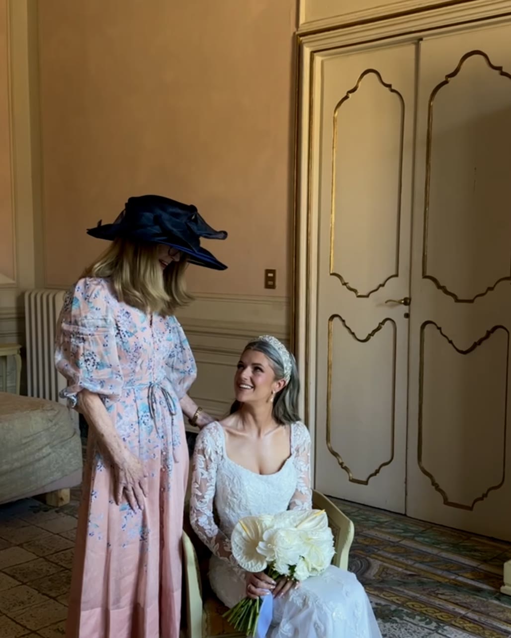 A bride looking up and laughing with her mum while getting ready