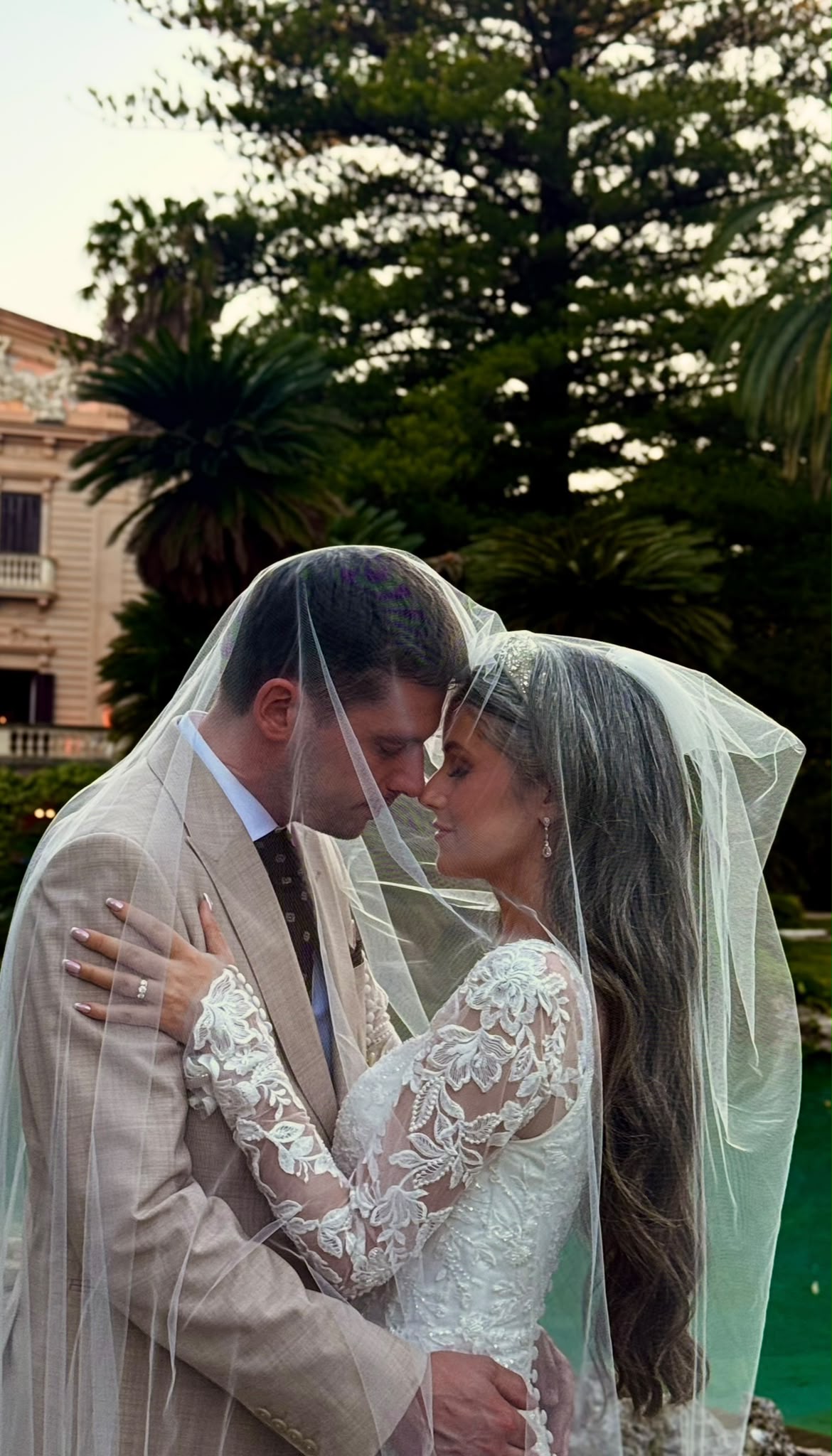 The couple close together under the bride's veil