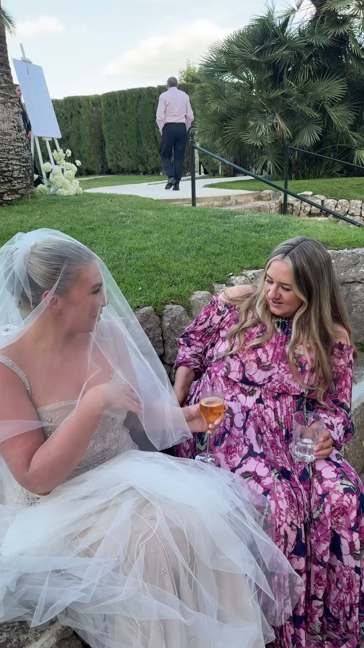 The bride laughing with a friend on the steps after the ceremony